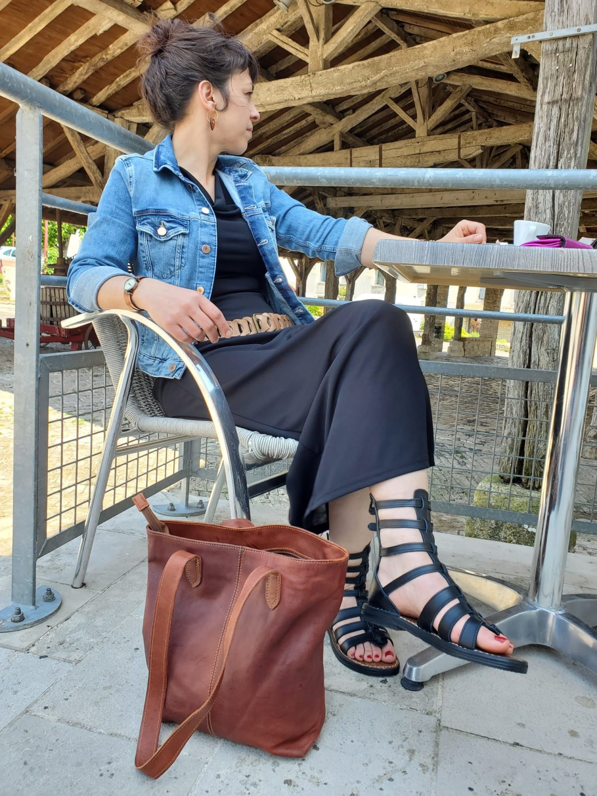 Ceinture large en cuir beige et à maillons portée sur une robe noire