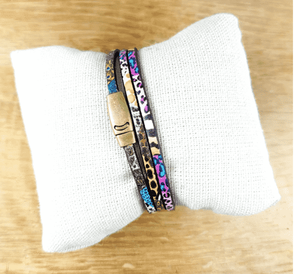 bracelet multirangs en cuir à motif sur coussin blanc avec fermoir finiton bronze