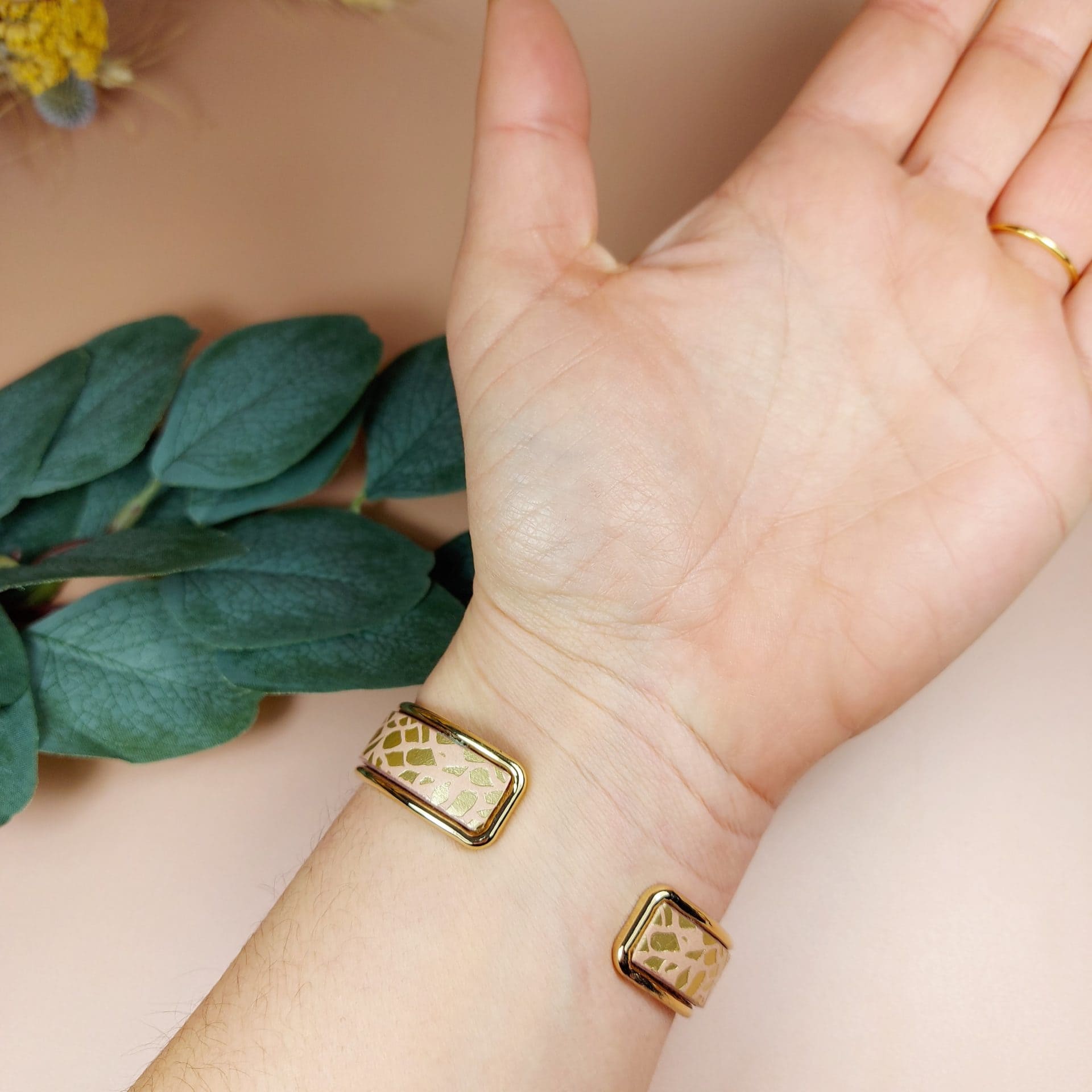 bracelet jonc doré avec lanière cuir nude porté au poignet d'une femme