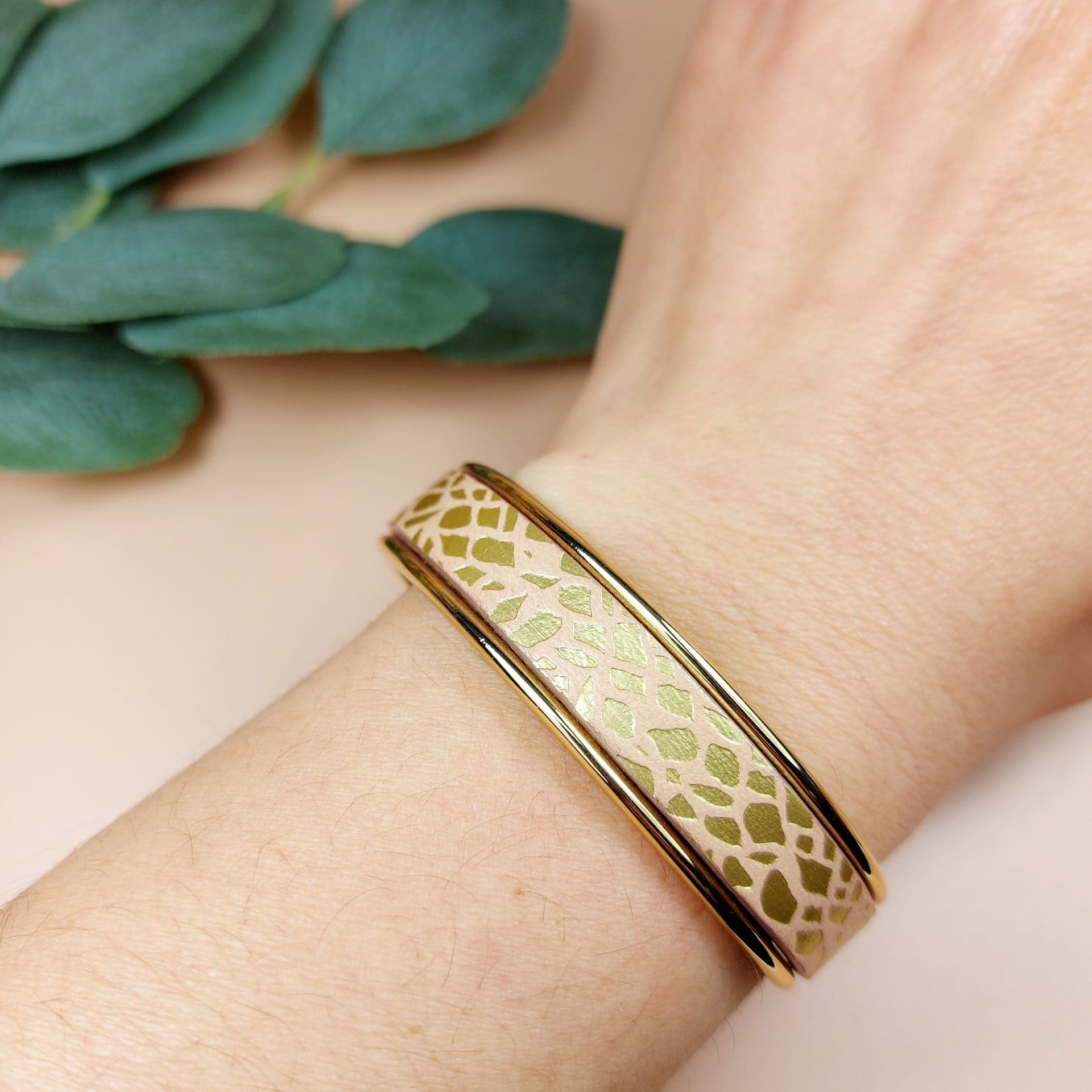 bracelet jonc doré avec lanière cuir nude porté au poignet d'une femme