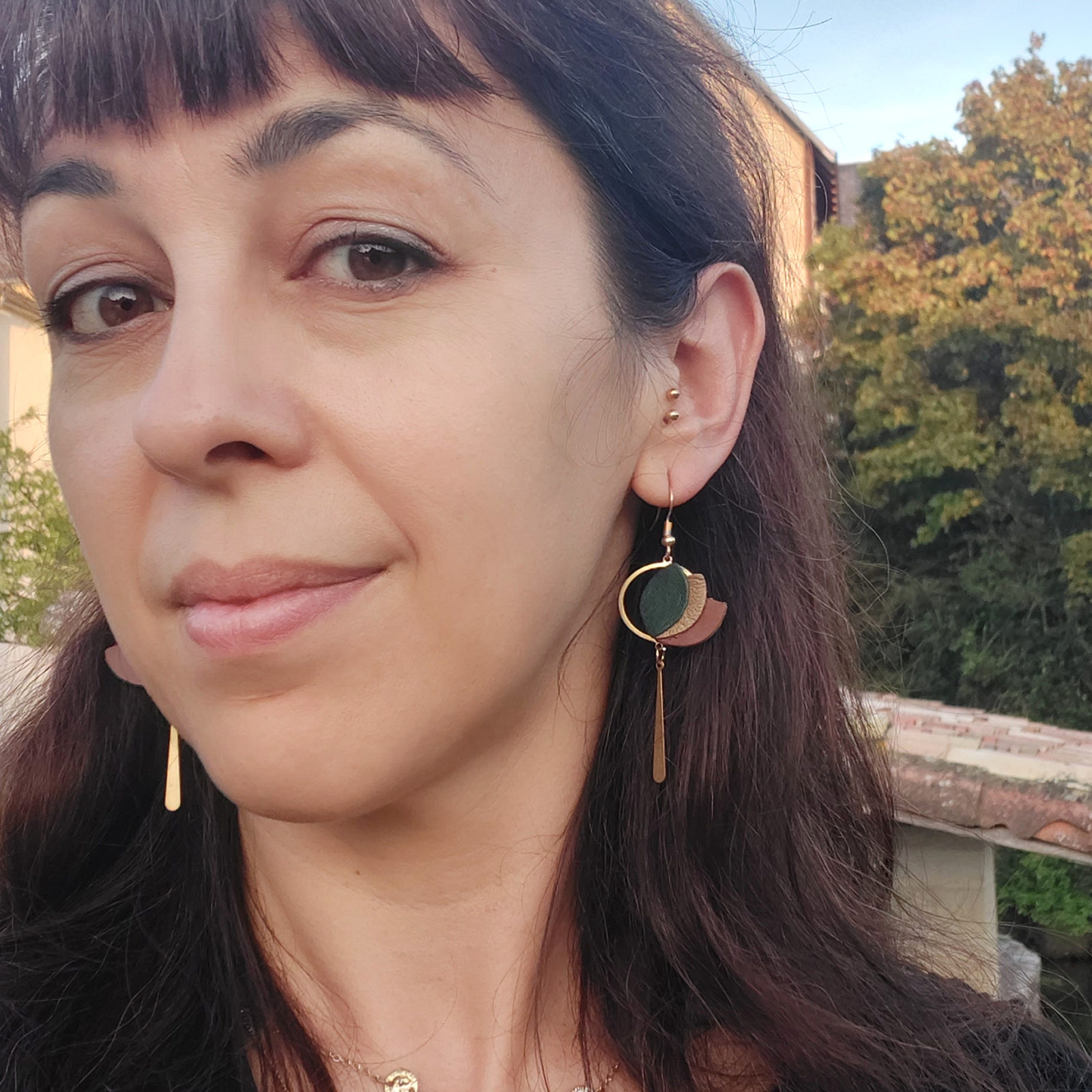 boucles d'oreilles upcyclées pendantes en cuir vert et bronze portées par une femme